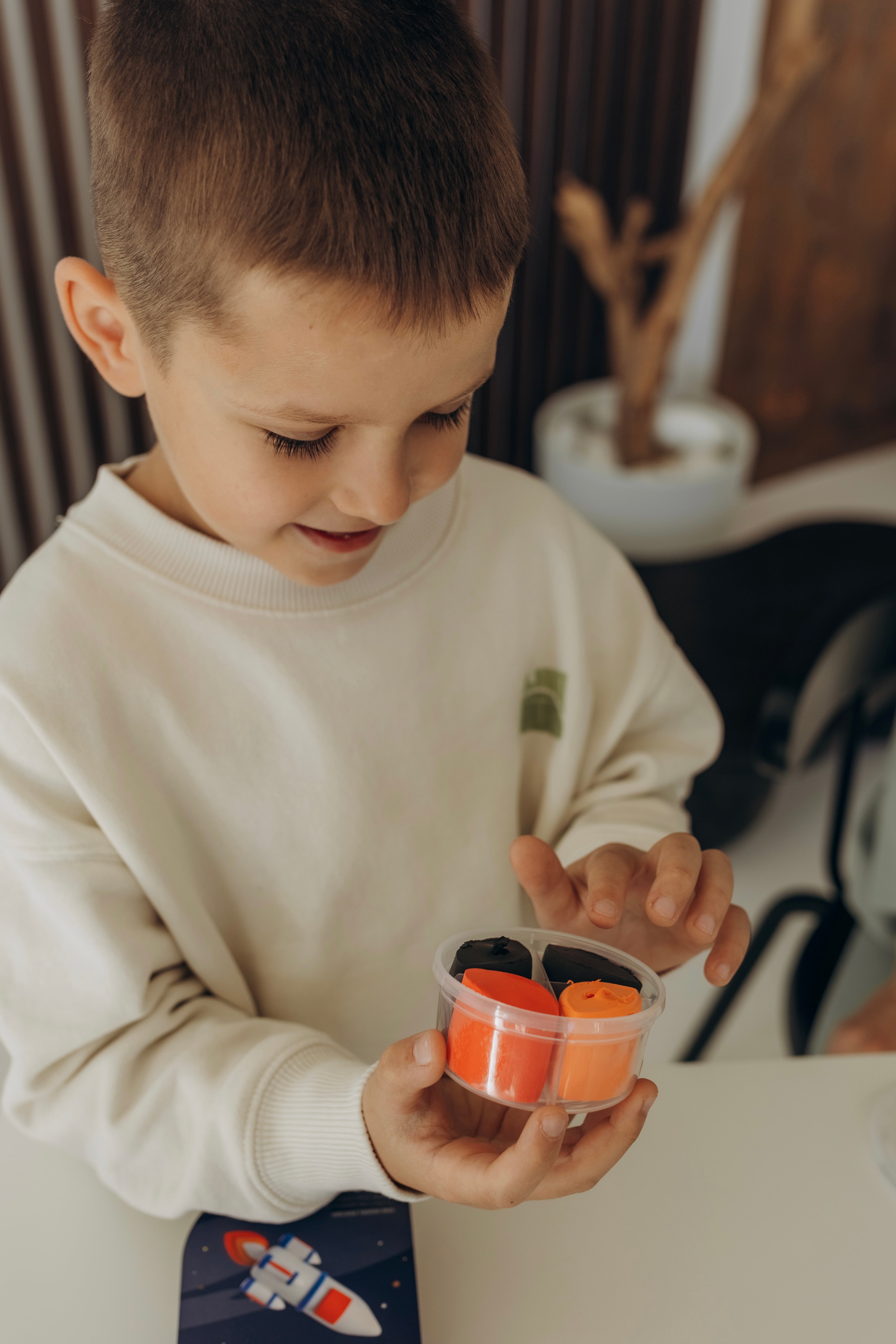 Child exploring colorful air-dry clay containers during hands-on creative play, screen-free activity that supports fine motor skills, focus and calm learning for children.