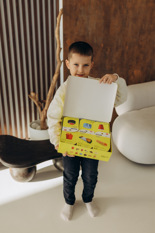 Happy child holding the Little Gourmet Air Dry Clay Kit gift box. A joyful Montessori-inspired activity box designed to spark imagination, confidence, and creativity. Perfect for birthdays, gifts, and screen-free family time. Eco-friendly, non-toxic materials for worry-free creative play.