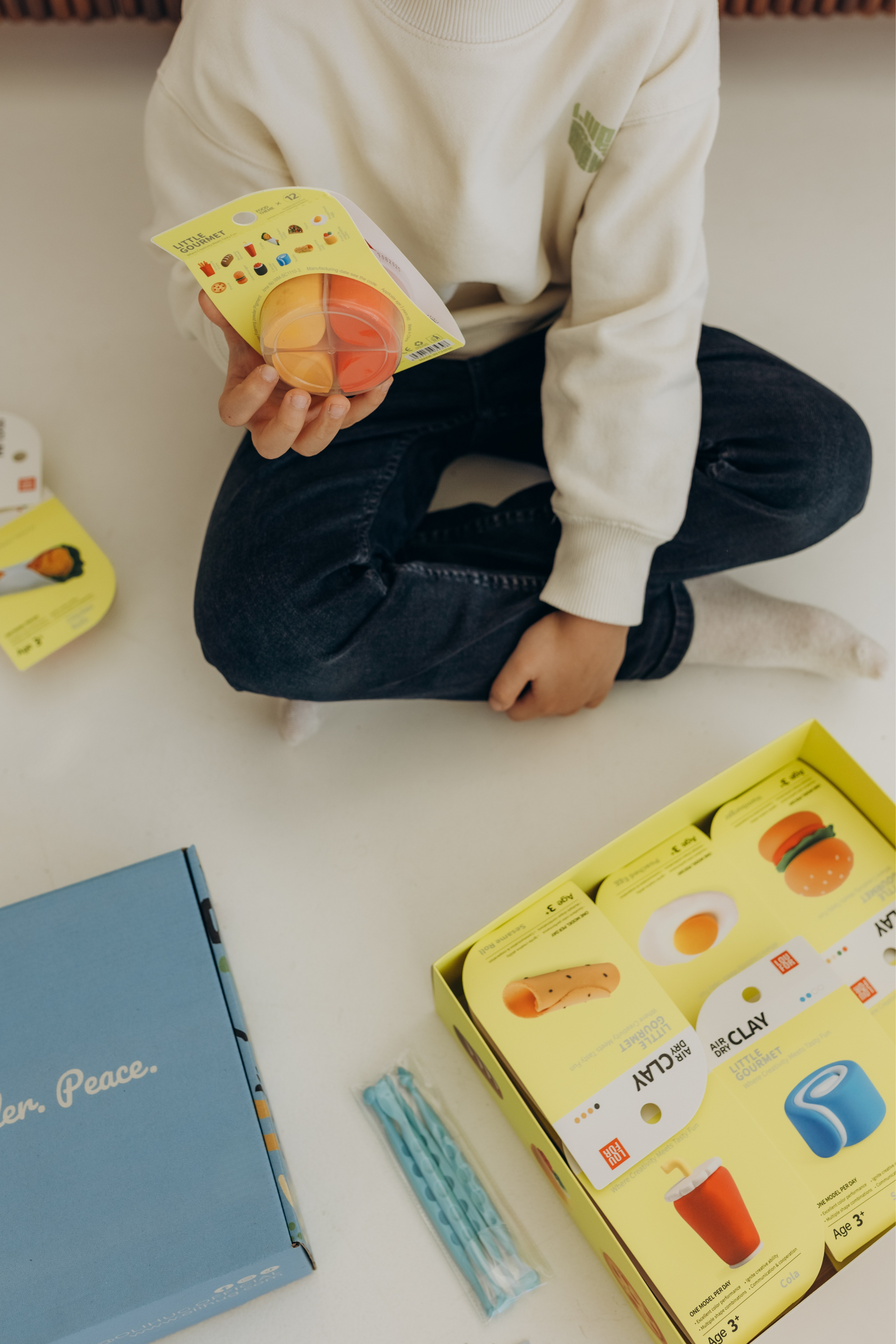 Child holding colorful OLIHUG air-dry clay pieces from a creative LOUFOR clay kit, close-up of hands-on screen-free play that supports fine motor skills, focus and imaginative learning for kids.